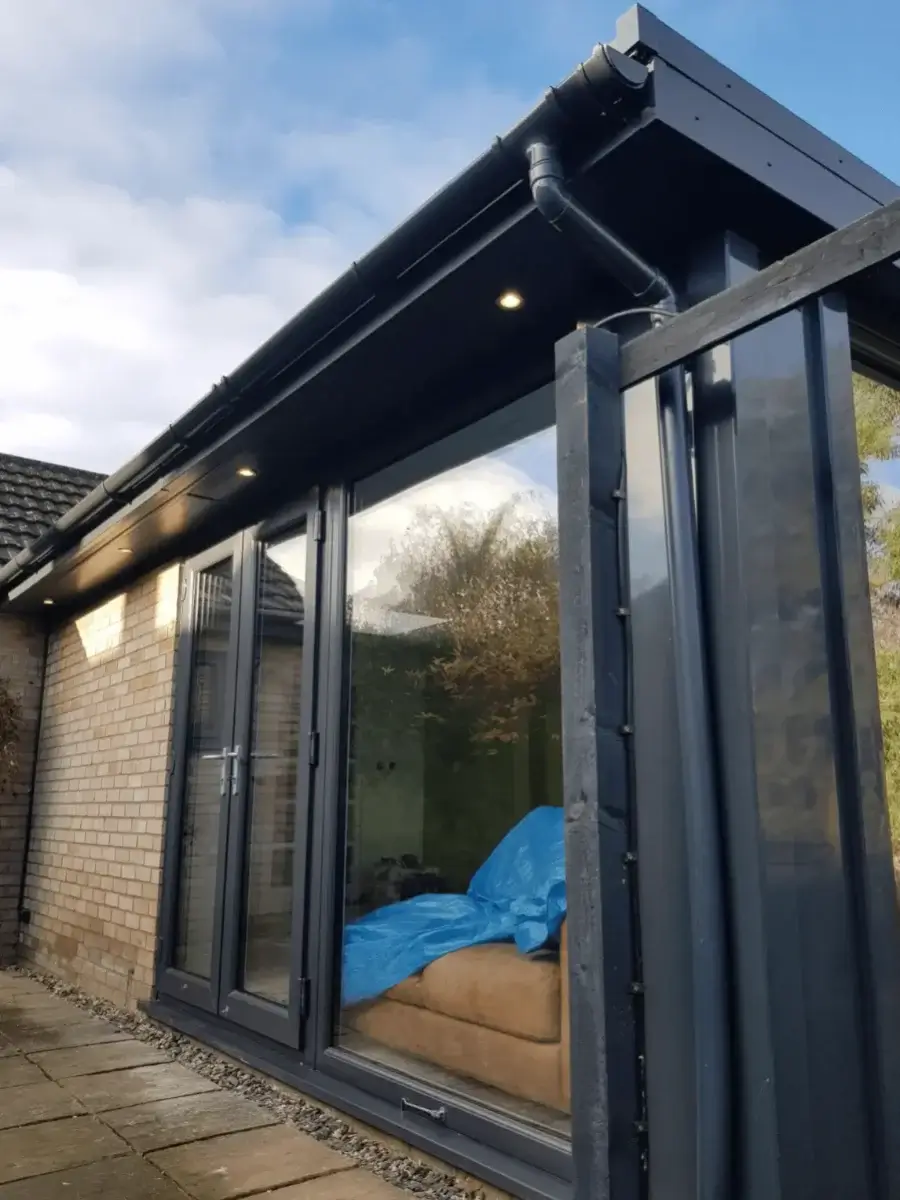Premium black uPVC fascia boards with integrated downlighting over sleek bifold patio doors. Installed by Norfolk Exterior Solutions